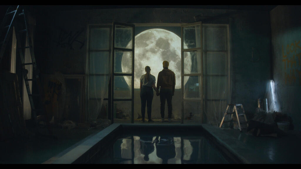 två personer som står och tittar på en stor måne